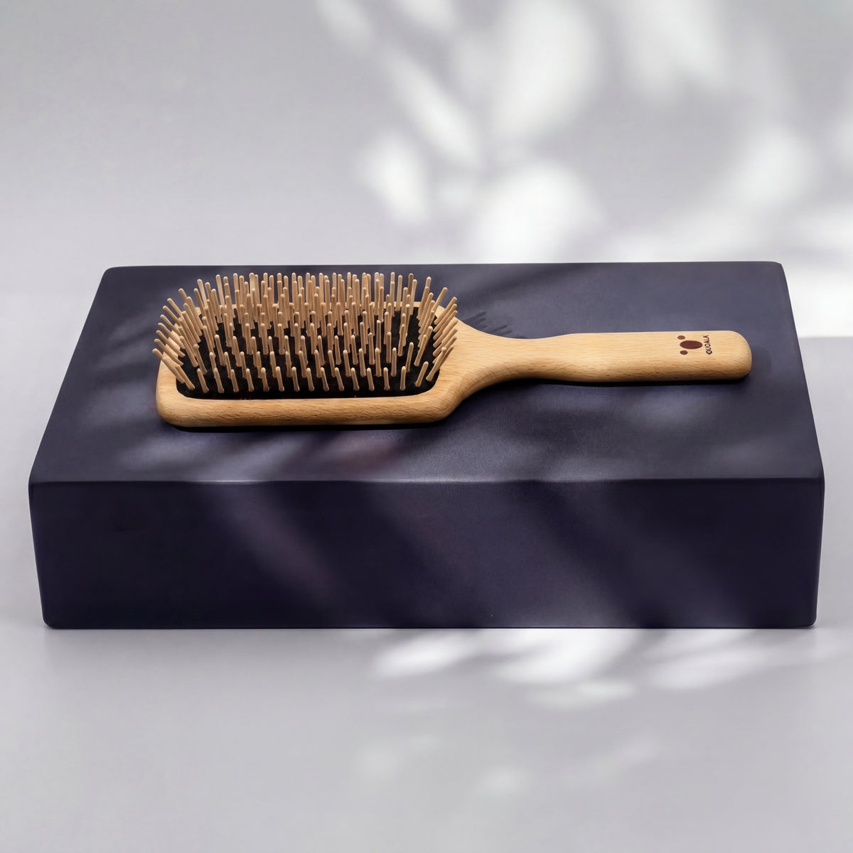 Paddle-Haarbürste aus FSC-Buchenholz mit Holzstiften aus Hainbuche auf einem schwarzen Luftkissen