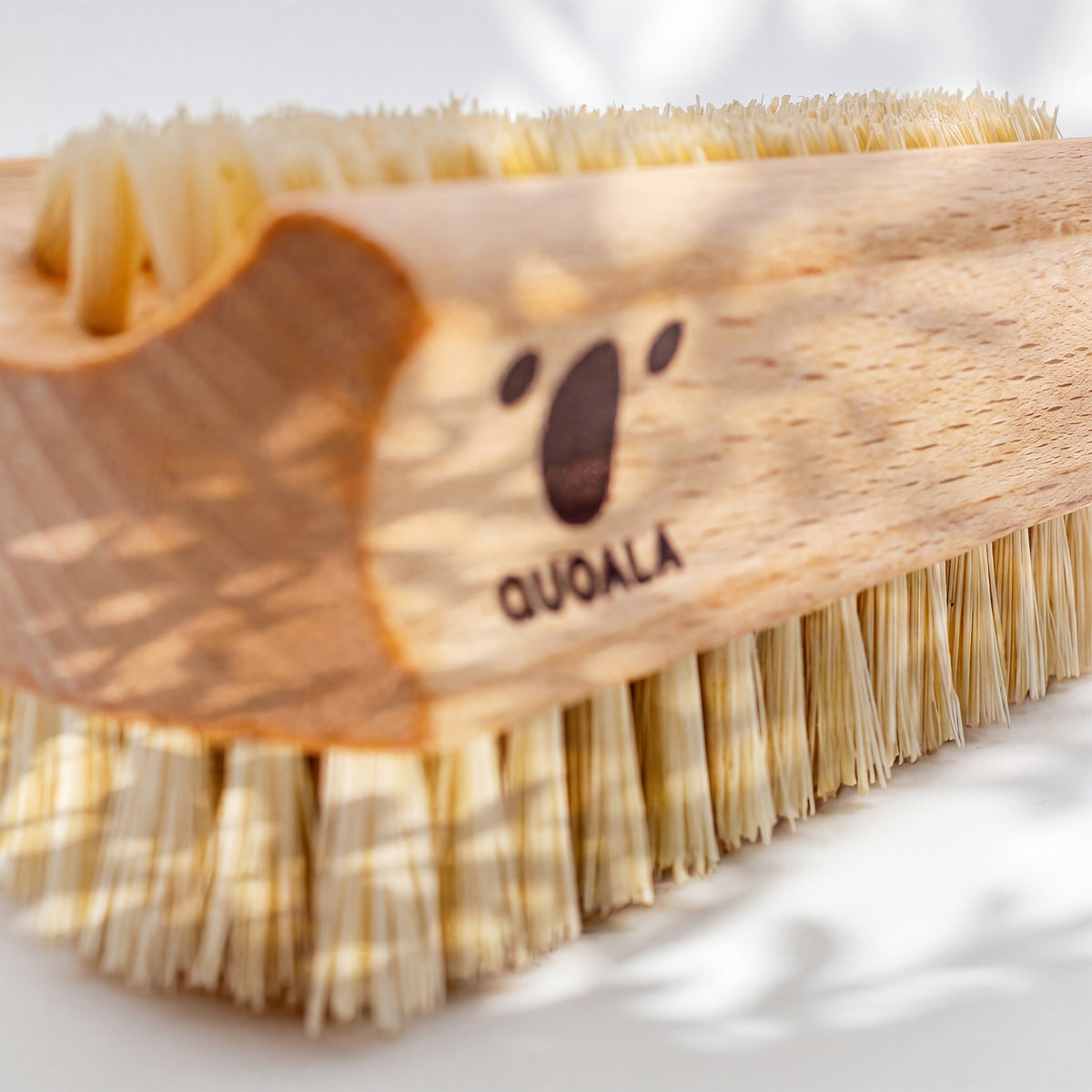 Längsseite der Hand- und Nagelbürste aus der Nähe: QUOALA-Logo im Holz, darunter die Fasern