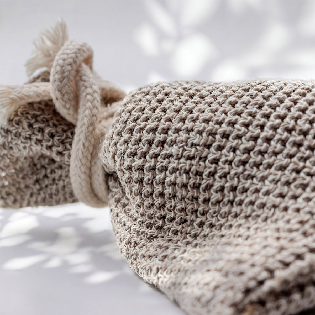 Strickmaschen des Seifensäckchens aus der Nähe: meliertes beige-braunes Garn und die geflochtene Kordel