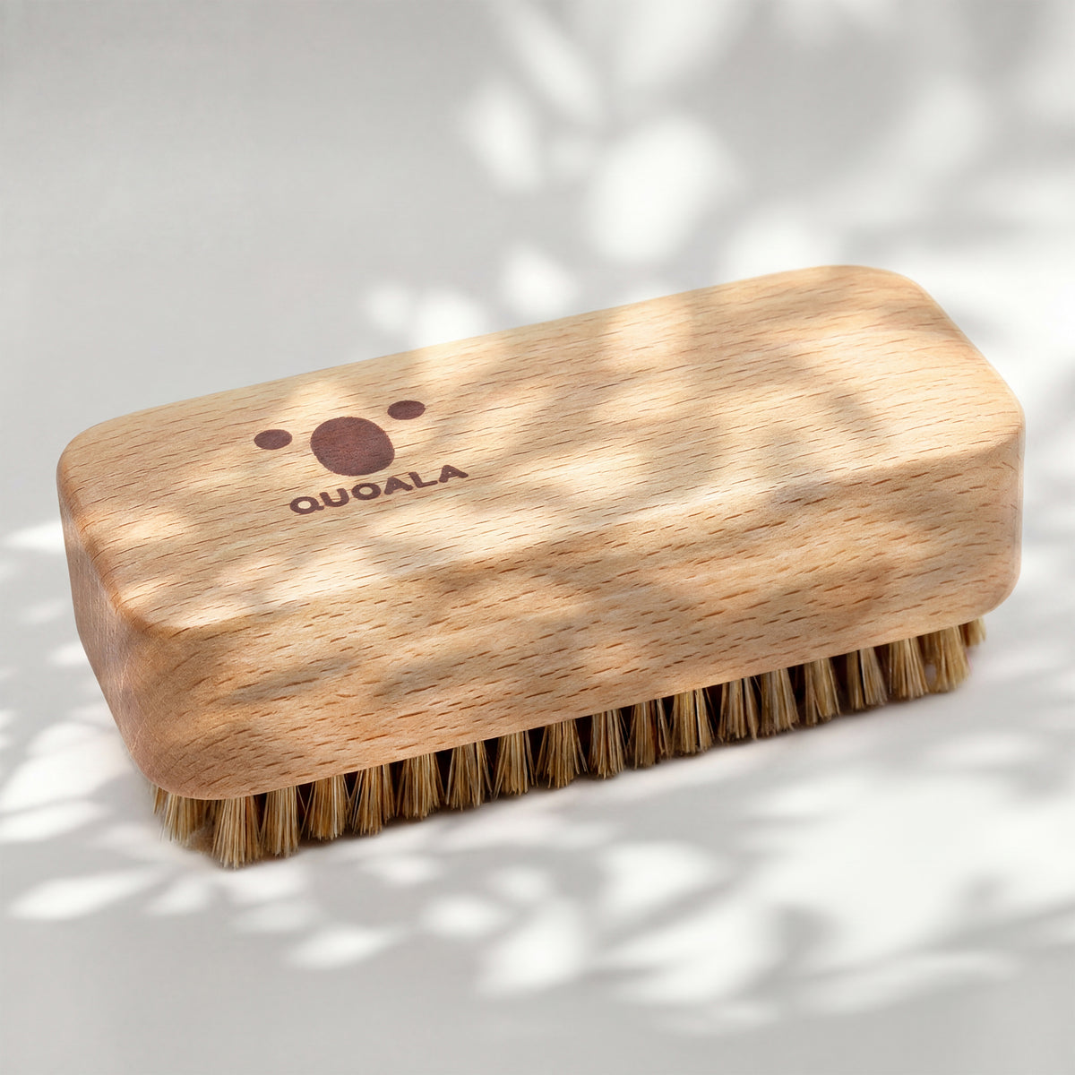 Handwerkerbürste schräg von oben, Holzblock mit QUOALA-Logo und sichtbarer Maserung auf der Oberseite